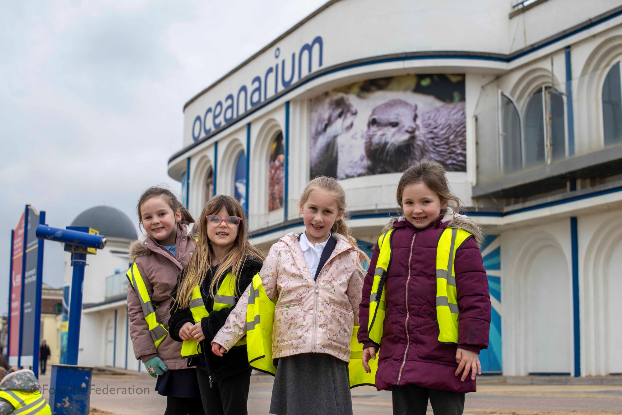 A group of children smile and pose in front of Bournemouth Oceanarium.